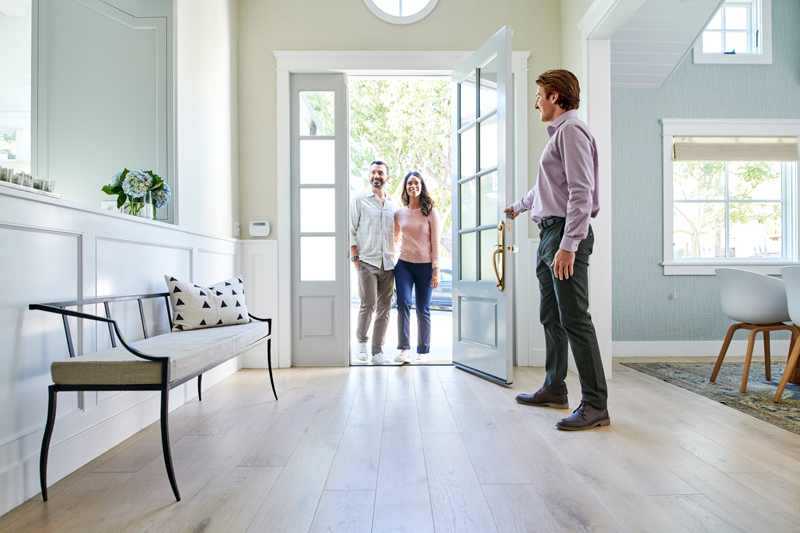 People entering a home to a waiting real estate agent
